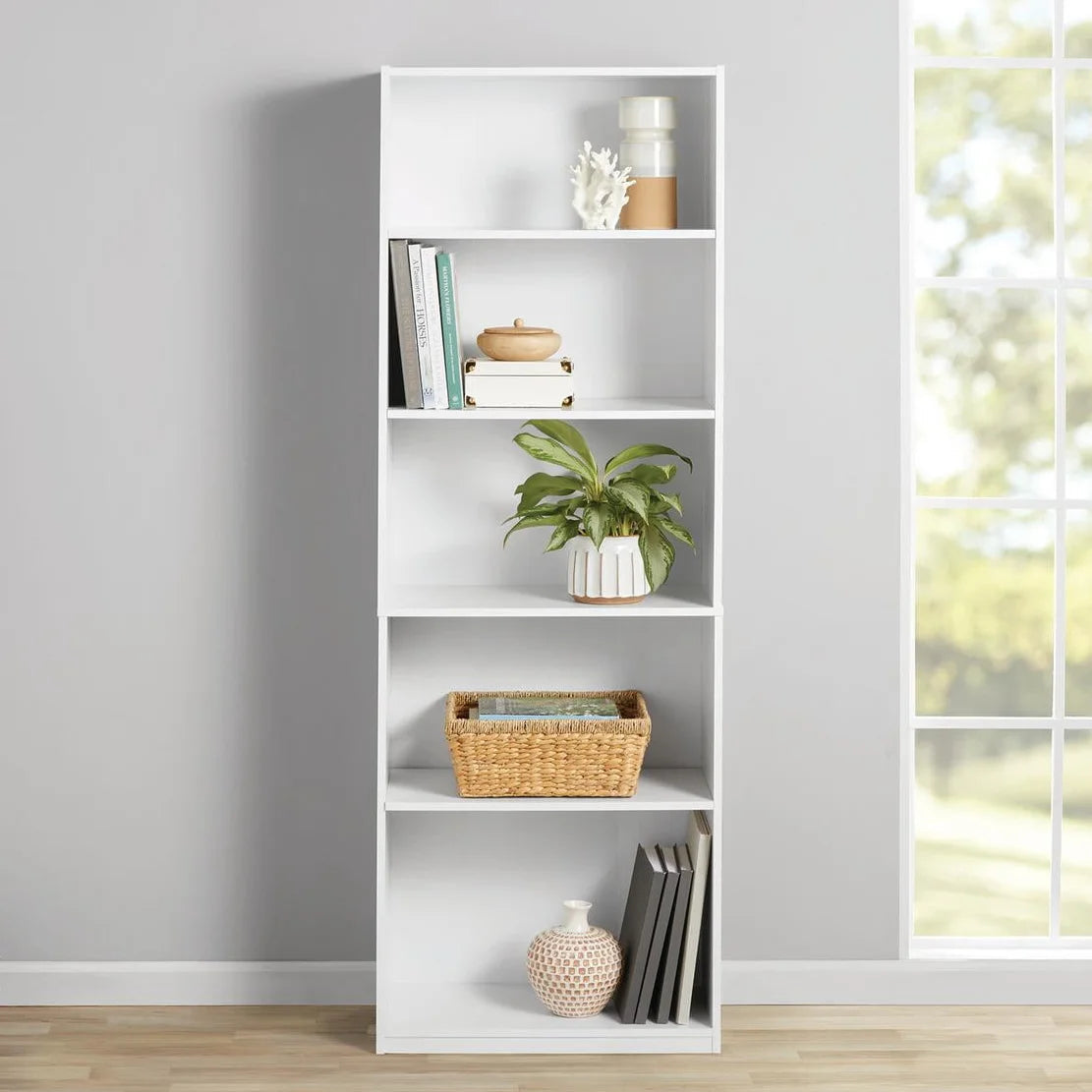 5-shelf white bookcase with adjustable and fixed shelves in a living room setting.