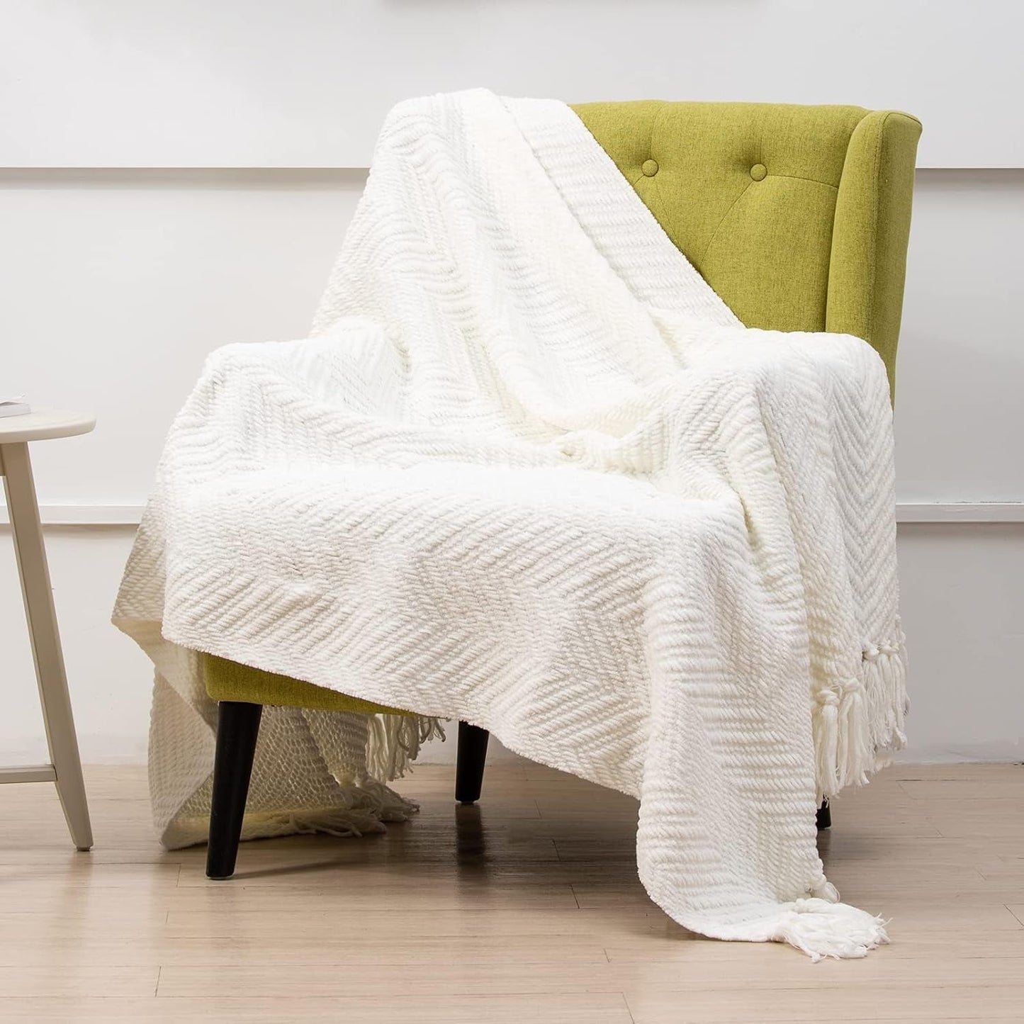 Cream herringbone faux cashmere throw blanket with tassels draped over a chair, ideal for farmhouse boho decor, size 50x60.